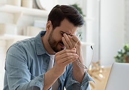 Young male squinching his eyes with his hand due to stress